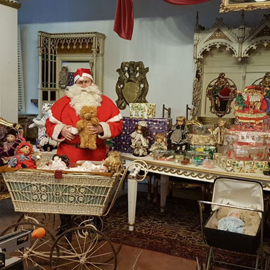 Der Weihnachtsmann steht mit vielen Geschenken in seiner Werkstatt im Königreich Romkerhall